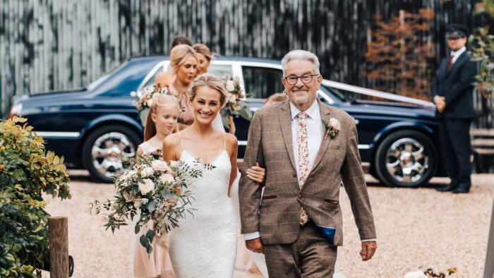 Smiling bride, father of the bride and her bridesmaids