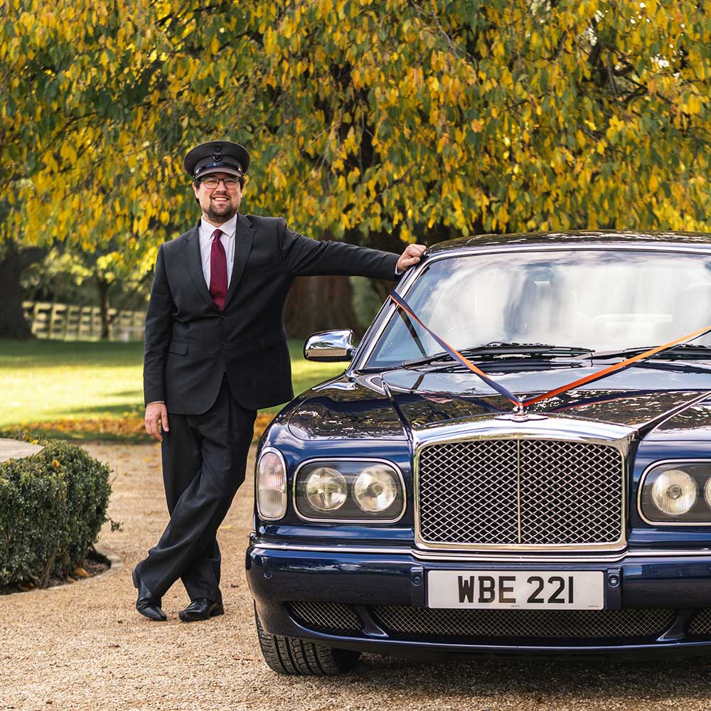 Image of proprietor of Azure Wedding Cars, Dan Goodrum, wearing a suit and his chauffeurs hat leaning one arm on his blue Bentley Arrange. Image credit: Lee Hawley Photography of Lee Hawley Photography - Creative, Candid, Natural - Wedding Photographer